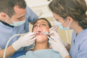 Dentist and Dental Assistant examining Patient teeth.